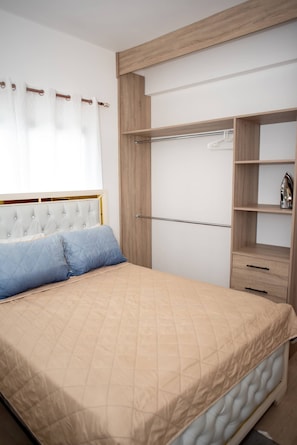 A bedroom with a bed, a wardrobe, and a window with curtains.