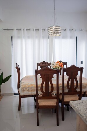 A dining area with a table and chairs, a chandelier, and a curtain.