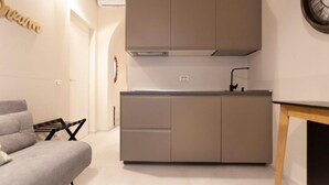 A compact kitchen with a grey countertop, a built-in oven, and a wall-mounted clock.