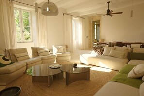 A spacious living room with a sectional sofa, a round coffee table, and a ceiling fan.