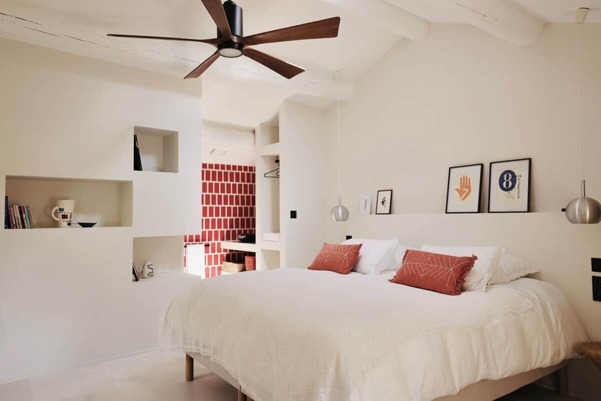Un dormitorio con cama, ventilador de techo y pared de ladrillo.