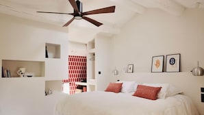 Een slaapkamer met een bed, een plafondventilator en een bakstenen muur.