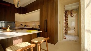 A modern kitchen with wooden cabinets, a white countertop, and two bar stools. - Louna room (Saint-Victor-la-Coste)