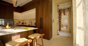 A modern kitchen with wooden cabinets, a white countertop, and two bar stools.