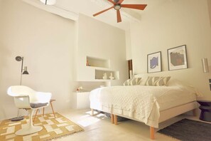 Une chambre à coucher comprenant un lit, une chaise, un ventilateur de plafond et une étagère avec des objets décoratifs.