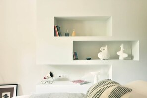 A minimalist room with white shelves, a bedside table, and a bed with a striped pillow. - Louna room (Saint-Victor-la-Coste)