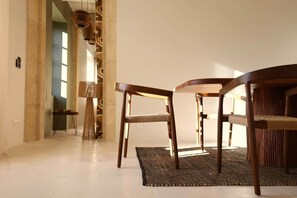 Un intérieur moderne avec un coin repas comprenant une table ronde et deux chaises, un tapis tissé et un lampadaire élancé.