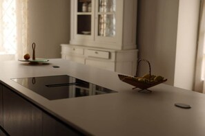 A modern kitchen with a built-in stovetop, a fruit bowl, and a cabinet in the background.