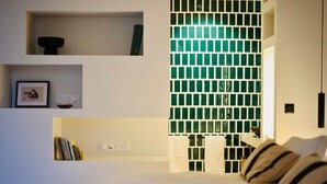Une chambre moderne avec un lit blanc, une bibliothèque et un mur recouvert de carreaux de verre verts.