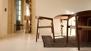 Un intérieur moderne avec un coin repas comprenant une table ronde et deux chaises, un tapis tissé et un lampadaire élancé.