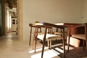 A dining area with wooden chairs and a woven table runner.