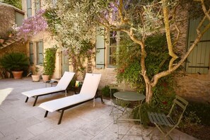 Une cour avec deux fauteuils de jardin, une petite table ronde et un banc.