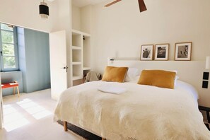Une chambre dotée d’un grand lit, d’une armoire intégrée, d’un bureau et d’une fenêtre laissant entrer la lumière naturelle.