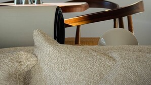 Un intérieur moderne avec une chaise en bois, une table ornée de vases en métal et un canapé à la texture intéressante.