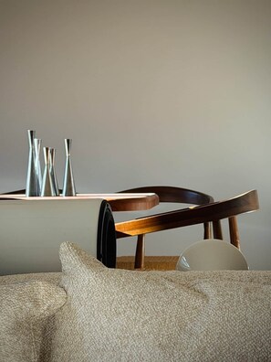 A modern interior with a wooden chair, a table with metal vases, and a textured sofa.