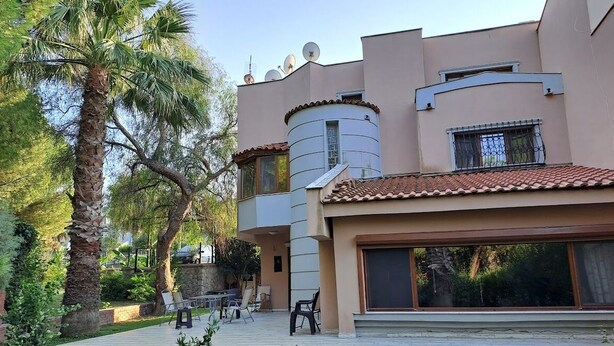 Un edificio moderno con techo plano, ventanas amplias y un patio con mobiliario exterior.