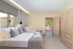 Ein modernes Schlafzimmer mit zwei Betten, einem Kleiderschrank und Blick ins Freie.