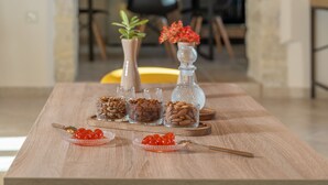 A wooden table with glass containers of nuts and red caviar, a spoon, and a decorative vase with red flowers. - Luxury Villa Dimitra With Private Swimming Pool (Hersonissos)