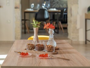 Ein Holztisch mit Glasbehältern voller Nüsse und Rote Bete, ein Löffel und eine dekorative Vase mit roten Blumen.