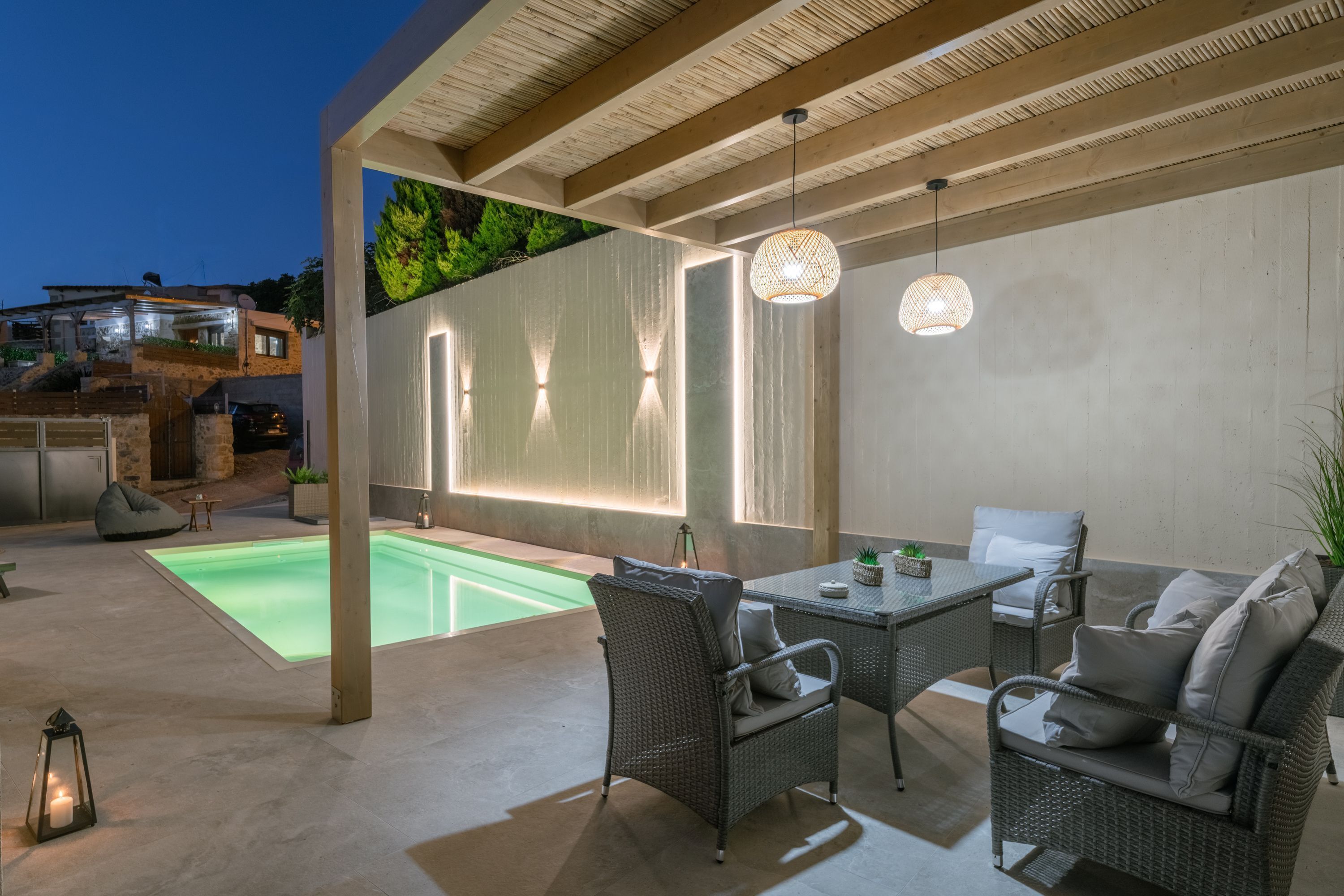 An outdoor patio with a pool, wicker furniture, and a hanging light fixture.