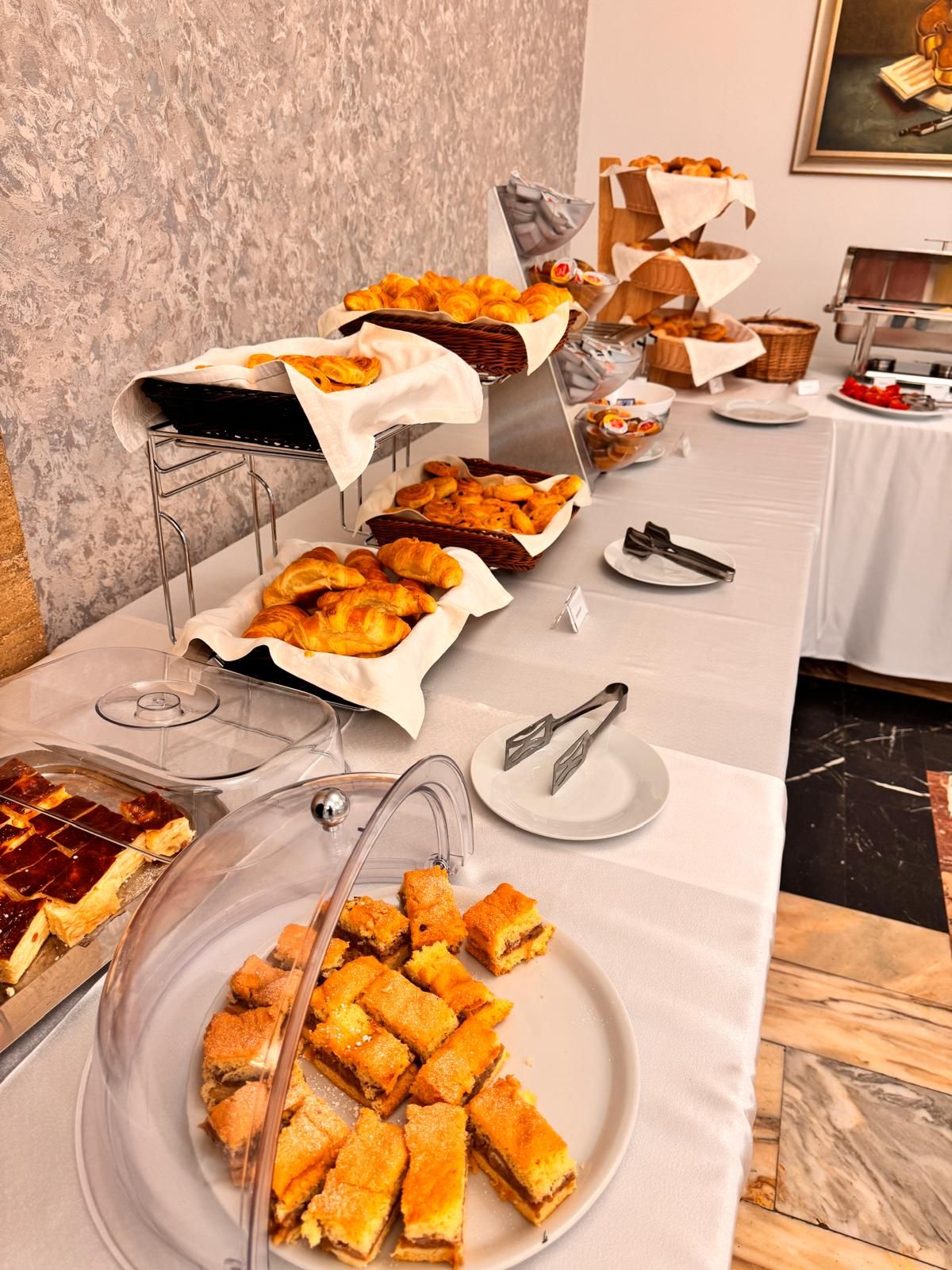 A buffet table with various food items, including pastries and desserts, arranged on a white tablecloth.