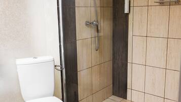 Et moderne badeværelse med toilet, bruseniche og flisebeklædte vægge.