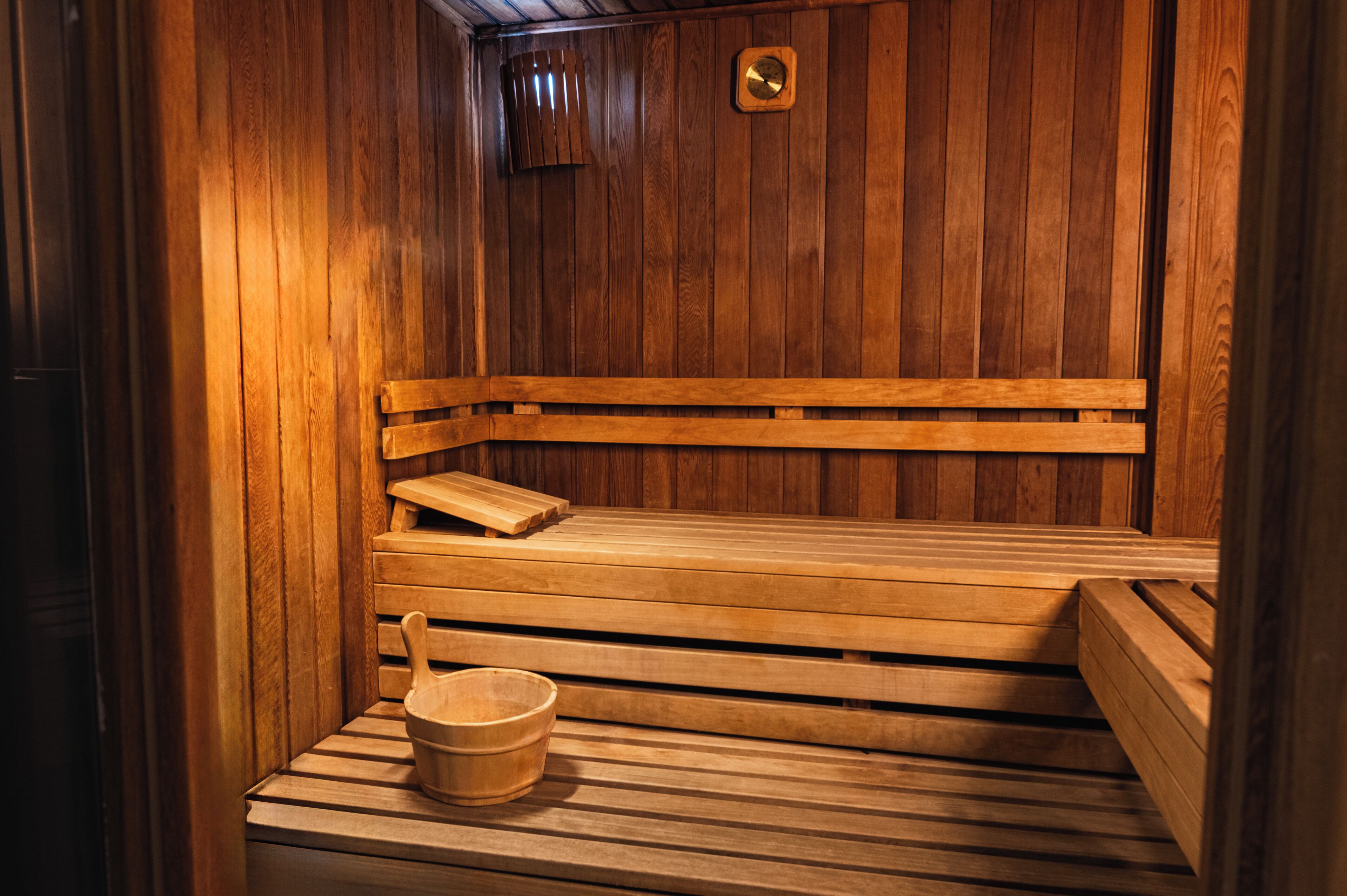 Un sauna en bois avec des bancs et un seau en bois.