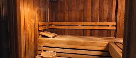 A wooden sauna with benches and a wooden bucket.