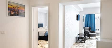 A hotel room with a bed, a chair, a table, and a painting on the wall.