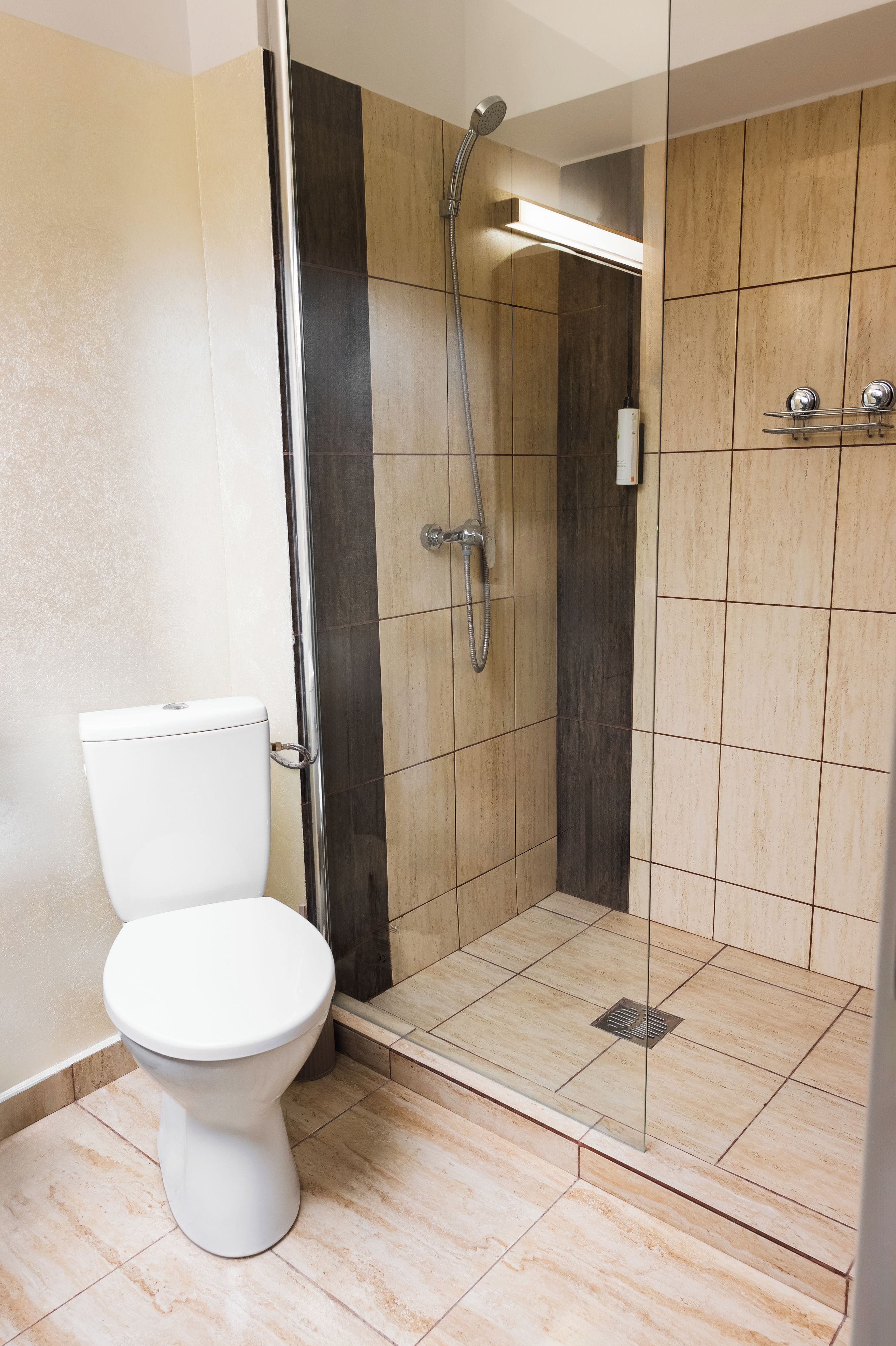 Une salle de bain moderne avec des toilettes, un espace douche et des murs carrelés.
