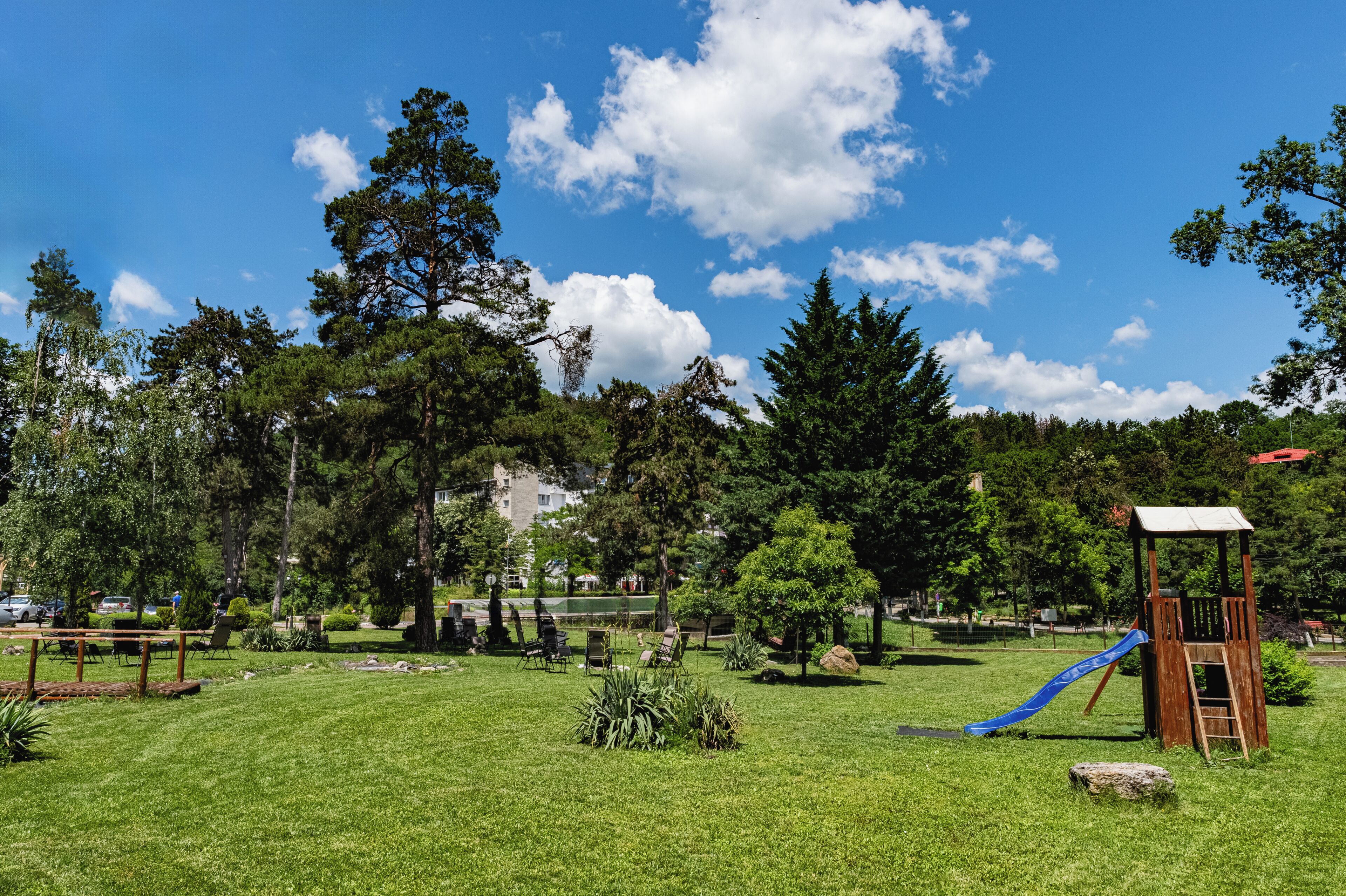 Un parque con área de juegos, que incluye un tobogán y una casita de madera.