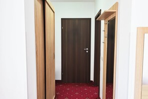 Un pasillo con una puerta de madera oscura, paredes de madera y una alfombra roja estampada.