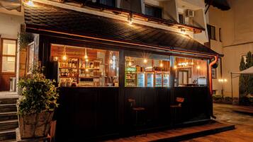 A bar with a wooden exterior, a counter with bottles, and a seating area.