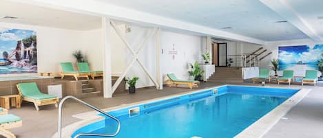 An indoor swimming pool with lounge chairs, a staircase, and wall art.
