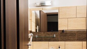Un baño con lavamanos, espejo, inodoro y un cubo de basura.