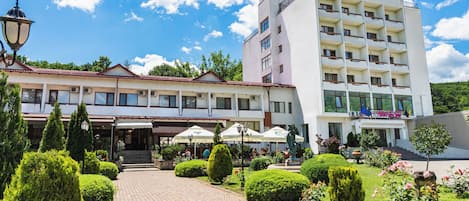 A hotel with a paved courtyard, outdoor seating, and a garden.