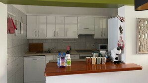 A kitchen with white cabinets, a wooden countertop, a coffee machine, and decorative items.