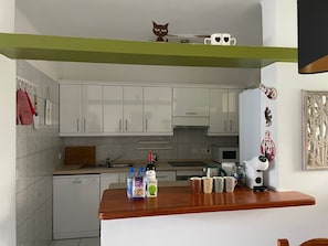 Eine Küche mit weißen Schränken, einer Holzausziehtafel, einer Kaffeemaschine und Dekorationselementen.