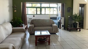 A living room with a sofa, a coffee table, a lamp, and a view of the outside.