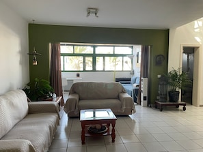 Ein Wohnzimmer mit einer Couch, einem Couchtisch, einer Lampe und Blick ins Freie.