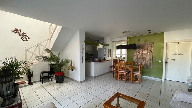 A spacious living area with a dining table, chairs, a sofa, and a coffee table.