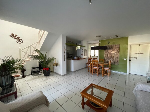 A spacious living area with a dining table, chairs, a sofa, and a coffee table.