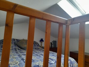 A bedroom with a wooden headboard, a patterned bedspread, a lamp, and a bookshelf. - Apartment, sea view, pets welcome - 4 guests (Noirmoutier-en-l'Île)