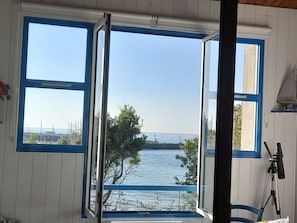 A room with a large window offering a view of a body of water, a chair, and a telescope. - Apartment, sea view, pets welcome - 4 guests (Noirmoutier-en-l'Île)