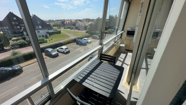 A balcony with a view of a street and parked cars. - La Corniche Large Studio (Courseulles-sur-Mer)