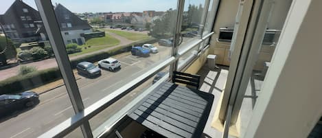 Un balcon donnant sur une rue et des voitures garées.
