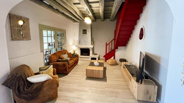 A living room with a fireplace, wooden flooring, a sofa, a coffee table, and a TV.