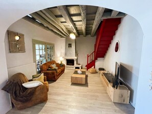 A living room with a fireplace, wooden flooring, a sofa, a coffee table, and a TV. - Charming house with pool and parking - 12 guests (Saint-Jean-Saint-Germain)