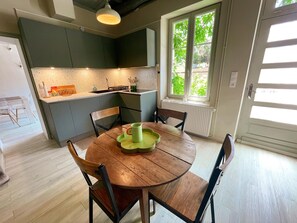 Una cocina moderna con armarios grises, una mesa de comedor de madera y una ventana con vistas a zonas verdes.