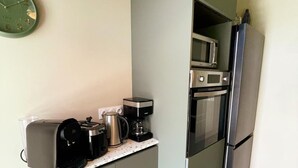 A kitchenette with a coffee maker, toaster, kettle, microwave, and refrigerator.